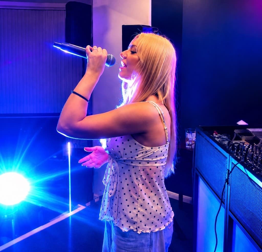 Abz performing live on stage with microphone under pink and blue lights